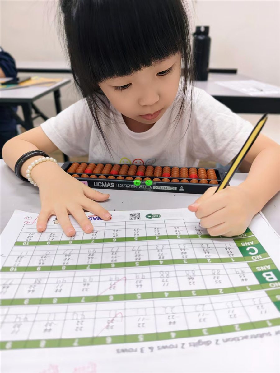 A student working on an arithmetic worksheet beside an abacus